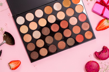 set of different eyeshadow in the Nude palette, Cute pink flat lay. Glamorous style, elements cosmetics and sweets on frameの写真素材