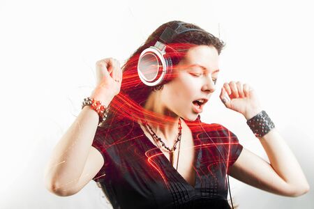 Girl fan sings and dances listening to music. Young brunette woman in big headphones enjoys music, double exposure, conceptの写真素材