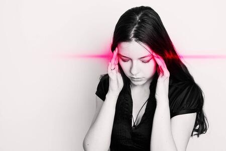 young woman is suffering from a headache. Portrait of a girl with pain points on her head. Migraines and blood pressure problems, conceptの写真素材