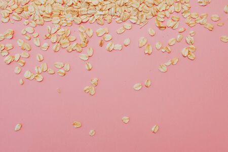 Fun healthy food, the concept. Grain oatmeal on a pink background. Oat flakes scattered, copy space