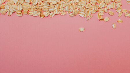 Fun healthy food, the concept. Grain oatmeal on a pink background. Oat flakes scattered, copy spaceの写真素材