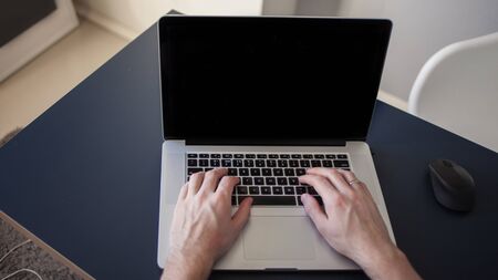 Designer for a laptop, a workplace for freelancers. A young man sitting at a table with a laptop