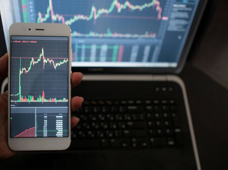Cross-platform services for trading on the exchange. Hand with the phone on the background of a...