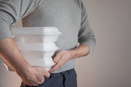 Food delivery. The courier man holding a container of food. Lunch from the restaurant, fast food conceptの写真素材