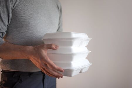 Food delivery. The courier man holding a container of food. Lunch from the restaurant, fast food...