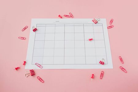 Blank paper calendar. Pink background. Bright pink clips and pins are scattered around.
