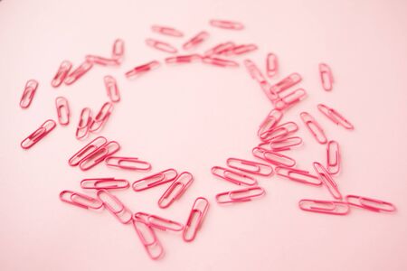 Scattered pink paper clips. Pink background. Flatlay. Copy space. empty round space.