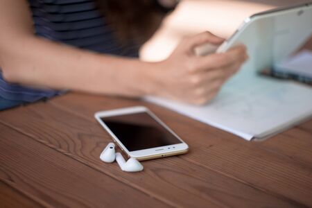 Neat young female hands with a minimalist manicure work on the tablet, next to it is a smartphone...
