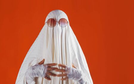 Happy Halloween. Cute funny Ghost on a bright orange background. Sheet Ghost costume, Halloween party carnivalの写真素材