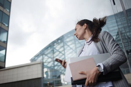 Career growth and ambitions, concept. Young businesswoman with a laptop in her hands on the background of the business center. Business and career in the company.の写真素材