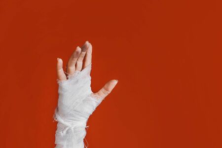 Halloween, costume image. The mummy's hand in bandages making gestures. The hand of the risen dead reaches up from the bottom, a bright orange backgroundの写真素材