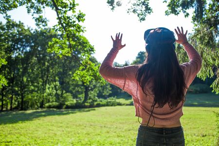 Virtual forest. A young woman in virtual reality glasses stands under the trees in a clearing, on a...