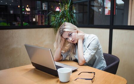 Stressful young business woman sitting at the table and working on a problematic issue. young...