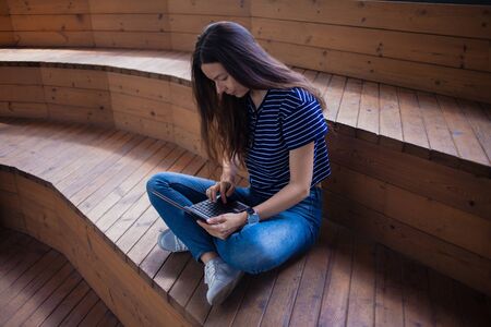 A brunette girl, a student with long hair, with a large wristwatch, with glasses sitting...