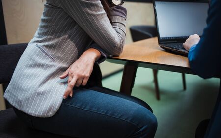 Hiring, job interview. Woman hides under the table fingers cross, excitement and stress. Deception when applying for a job.の写真素材