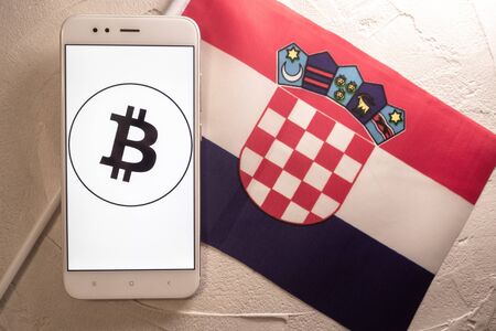 Cryptocurrency and government regulation, concept. Modern economy, smartphone with bitcoin sign on the screen on the background of the flag of Croatiaの写真素材