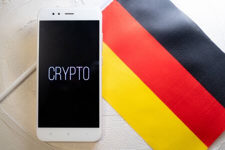 Cryptocurrency and government regulation, concept. Modern economy, smartphone with bitcoin sign on the screen on the background of the flag of Germanyの写真素材