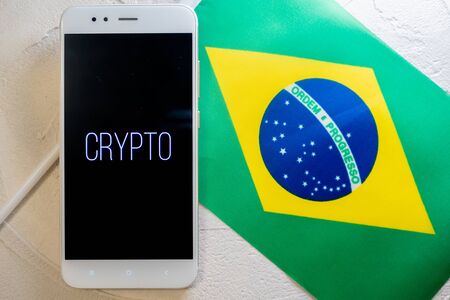 Cryptocurrency and government regulation, concept. Modern economy, smartphone with bitcoin sign on the screen on the background of the flag of Brazilの写真素材
