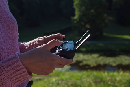 Female hands with a neat manicure hold a drone control panel with drumbo antennas and a larger...