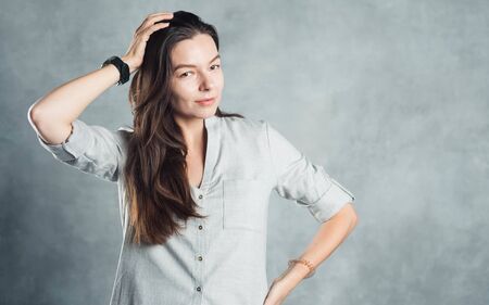 Young brunette woman in casual clothes, self-confidence. Smiling and calm girl on a gray textured background.の写真素材