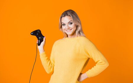 Girl gamer. Play computer games, a modern hobby and sport. A young woman with a gamepad on a yellow...