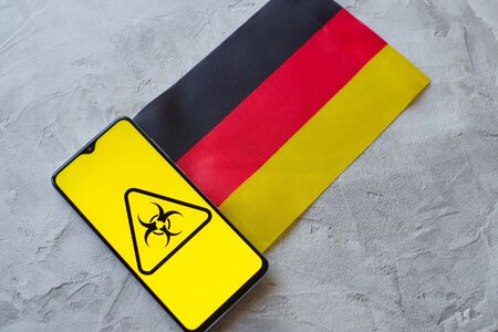 Epidemiological situation in the country Germany. Flag and smartphone with news and a biohazard symbol. The pandemic virus, conceptの写真素材