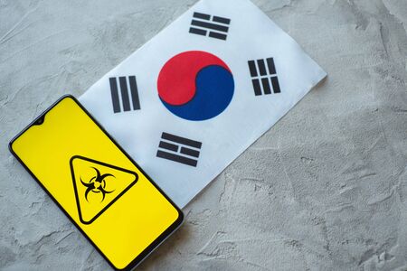 Epidemiological situation in the country Republic of Korea. Flag and smartphone with news and a biohazard symbol. The pandemic virus, conceptの写真素材