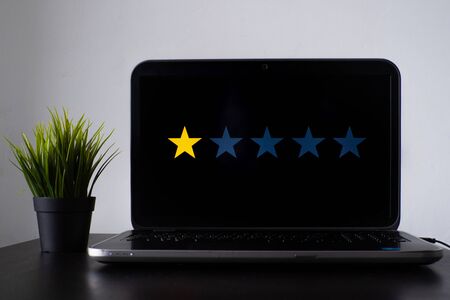 Ranking of a product or service by quality, user feedback or quality control, concept. One of five stars on the laptop screenの写真素材