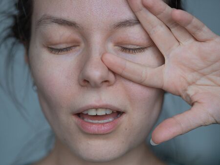 happy young woman laughs and makes a hand gesture, two fingers up. Super close-up, portrait without...