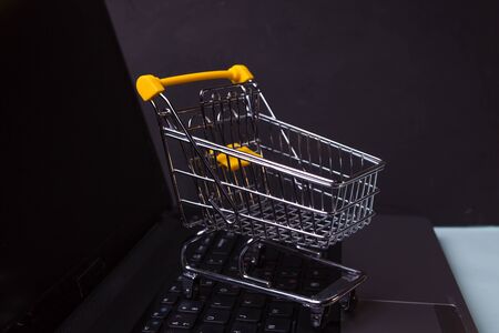 E-Commerce, concept. Online shopping, shopping cart on laptop keyboard.