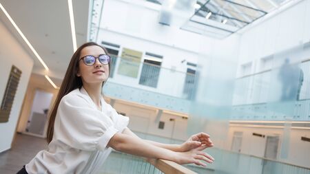 Portrait of a young positive business woman. A girl in glasses and a white shirt, the interior of a...