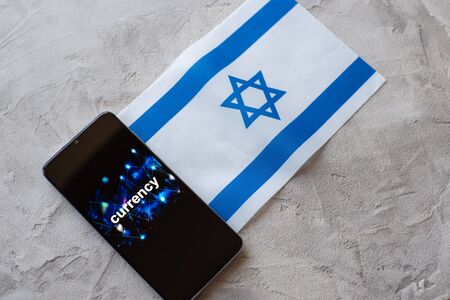 Trading on the currency exchange in the Israel, concept. Smartphone with an inscription on the screen and the flag of Israelの写真素材