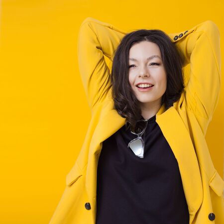 Stylish young woman in a yellow jacket on a yellow background, bright and trendy portraitの写真素材
