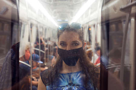 young woman with a mask on her face, protection from the virus. A girl in a nearby subway car in a protective mask uses a smartphone. Portrait with a noise and blur effectの写真素材