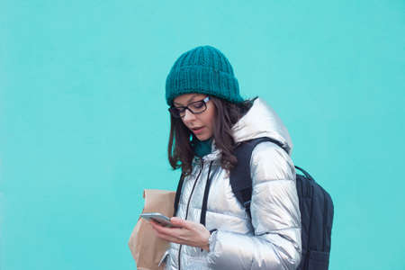 courier or volunteer carries food in a paper bag. A young woman in a warm jacket holds a parcel and...