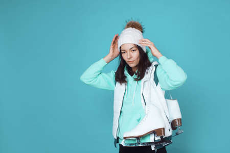 Winter hobby, ice skating. A young woman in a sweatshirt and a knitted hat prepared skates for figure skating.の写真素材