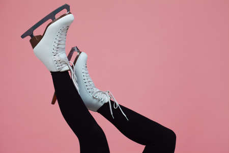 Figure skating is a winter sport and leisure. Women's feet in ice dancing skates. Female figure skater, legs on a pink background.の写真素材
