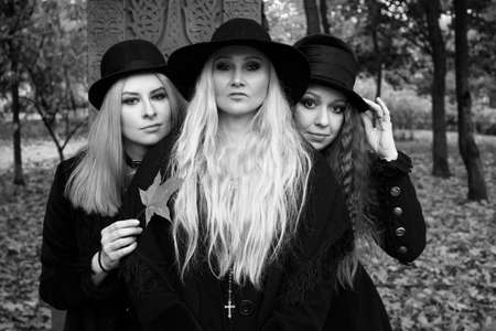 Coven of witches, a group of different friends as witches meet Halloween. Young women in black clothes and hatsの写真素材
