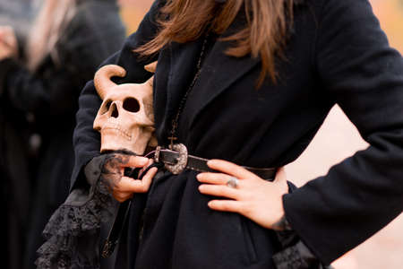 a witch holds in hands the skull of a demon. Halloween, a young woman at the carnival like a witch,...