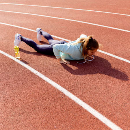 Outdoor fitness, public sports field. A young sportswoman does a workout on the street, a healthy...