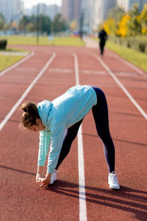 Outdoor fitness, public sports field. A young sportswoman does a workout on the street, a healthy...