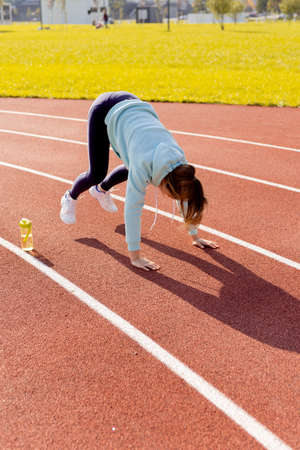 Outdoor fitness, public sports field. A young sportswoman does a workout on the street, a healthy lifestyle.の写真素材