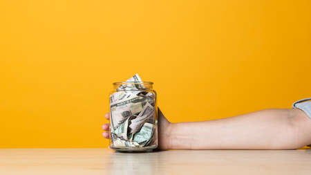 Money in the Bank, deposits and personal accounts, concept. Investments and savings, bright yellow background. A hand reaches out to cashの写真素材