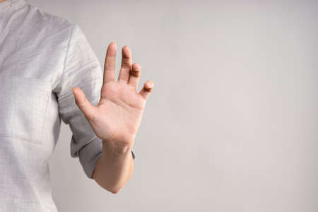 Poke at the screen, open your palm, use the virtual interface. businesswoman in a casual gray shirt makes a hand gestureの写真素材