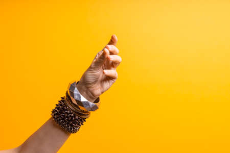 Hand gestures. Womens hand with lots of bracelets, youth fun style. bright yellow backgroundの写真素材