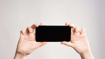Use your smartphone horizontally, take panoramic photos, or watch videos. Phone in womens hands....