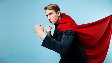 The superhero protects. A young man in a suit with a red cape, superman. Strong and fairの写真素材