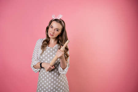 young charming woman pastry chef with a rolling pin in her hands. A cook in a polka-dot apron....