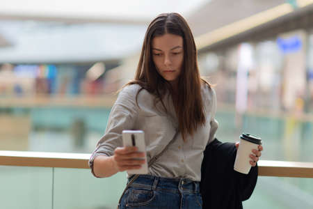 Young woman in casual clothing in a shopping center, shopping. Brunette with a phone in the Mall...