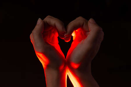 Two hands folded in the shape of a heart, light inside. Clench your hands, symbol of love.の写真素材